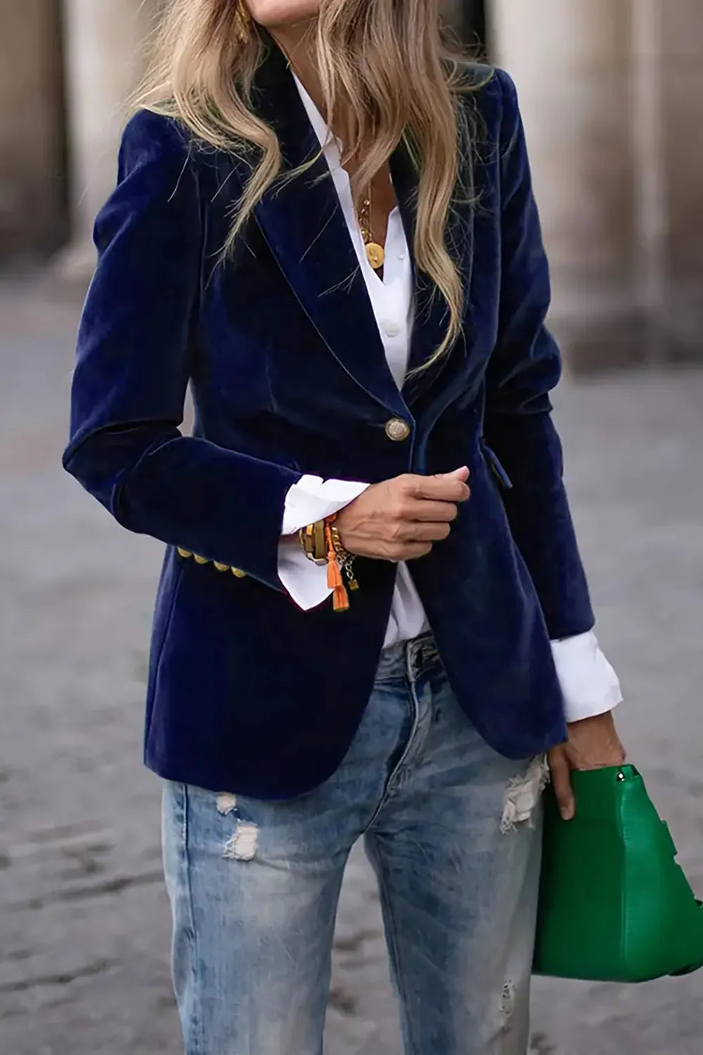 Woman wearing navy one button lapel collar long sleeve blazer with white shirt and jeans, holding green handbag